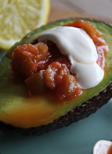 Nærbilde av halv avokado med salsa og rømme